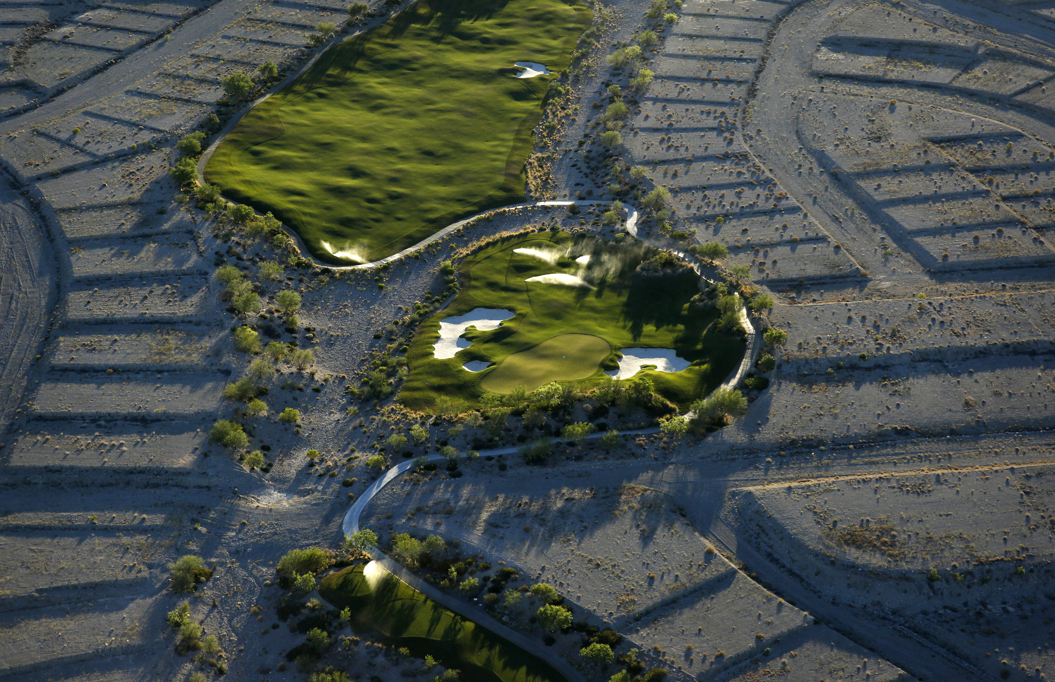 Shrubs grow on empty housing pads around a hole at the Coyote Springs golf course.