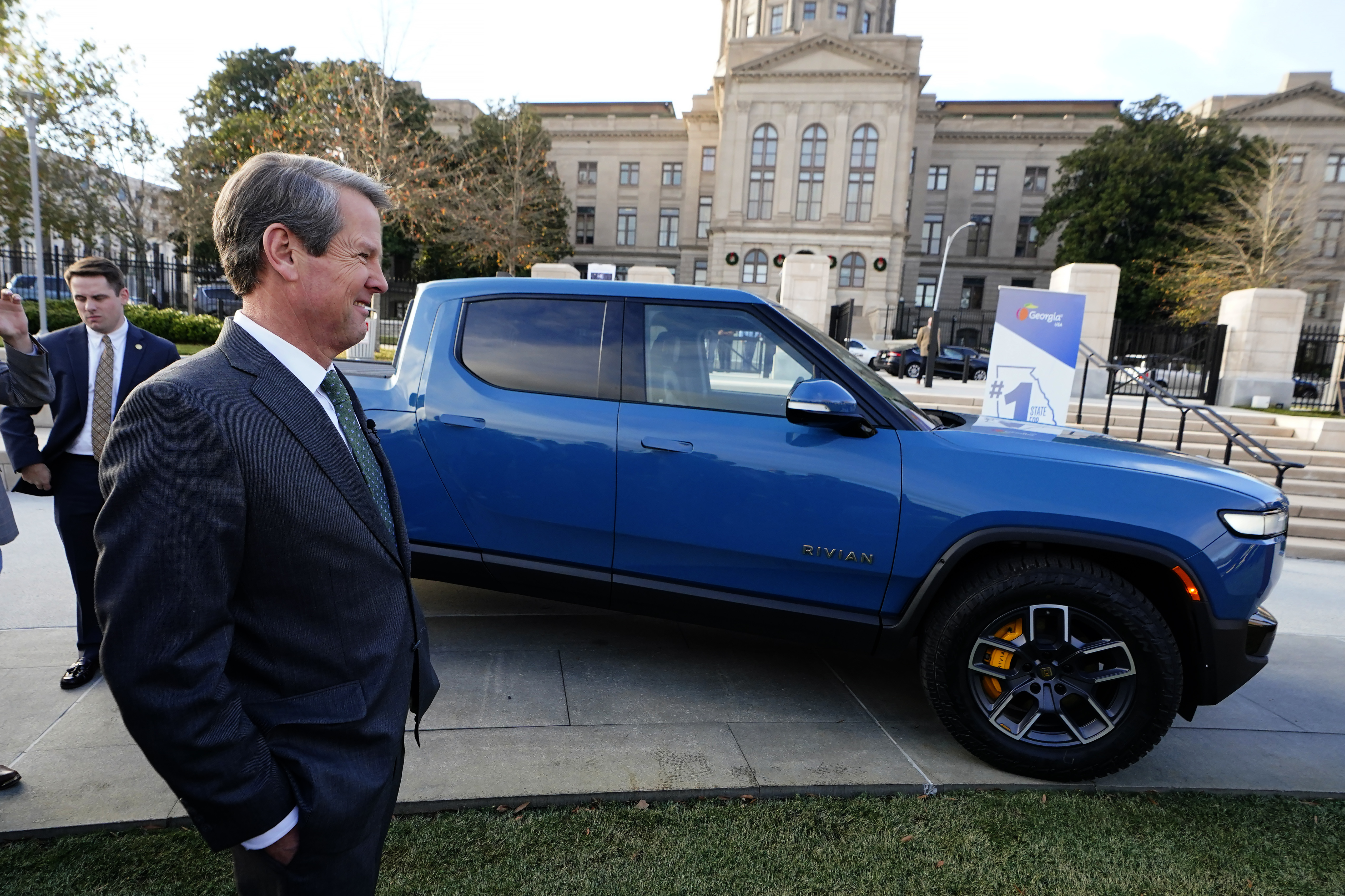 Georgia Gov. Brian Kemp smiles as he stands next to a Rivian electric truck during a ceremony to announce plans by the electric truck-maker plans to build a plant east of Atlanta. Georgia Gov. Brian Kemp smiles as he stands next to a Rivian electric truck during a ceremony to announce plans by the electric truck-maker plans to build a plant east of Atlanta.